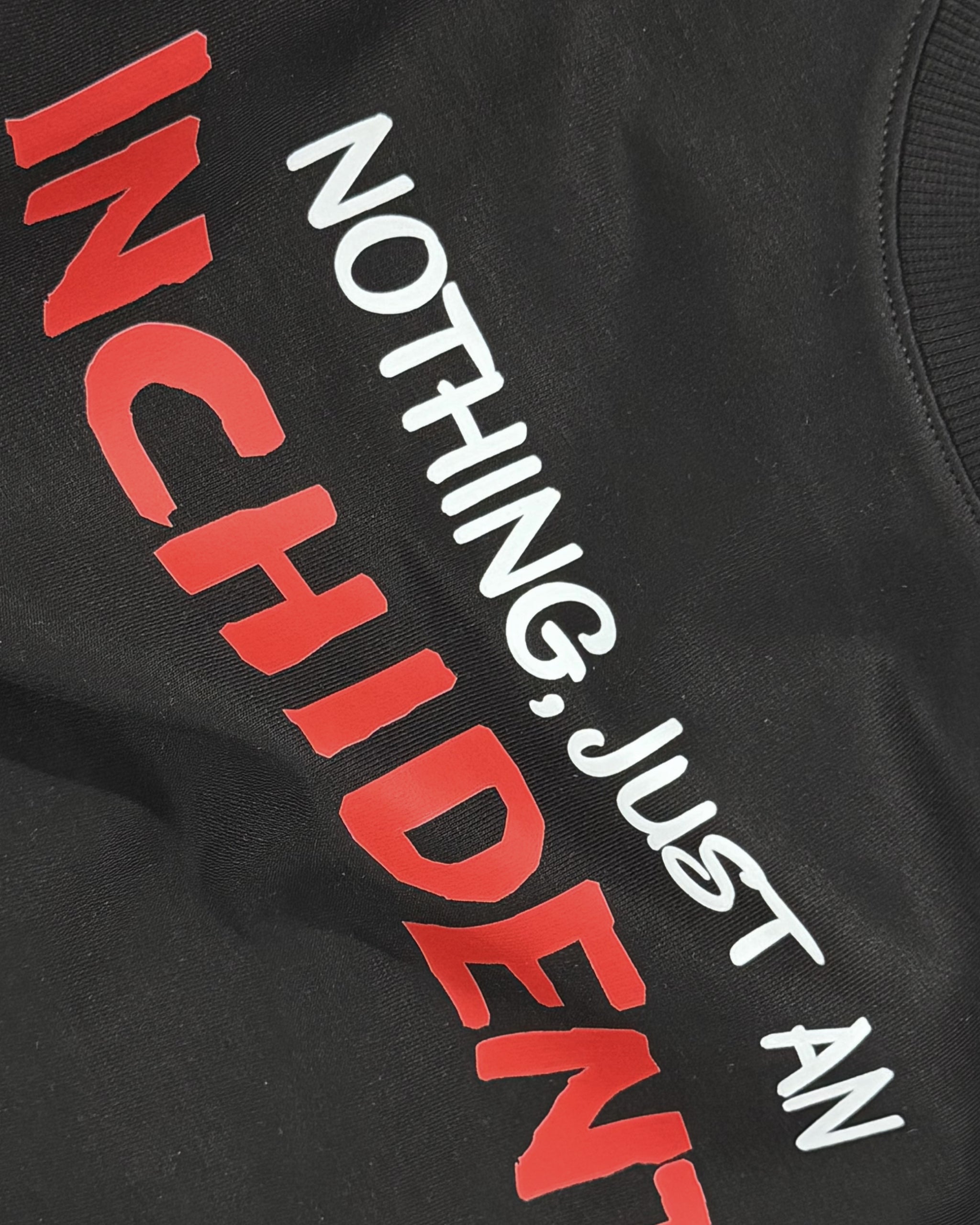 Closeup of F1 Black Unisex Oversized fit Tshirt by Turn 1 Brand, an F1 Apparel brand of India. Charles Leclerc fan tshirt with his quote "Nothing, Just an Inchident!" on front.