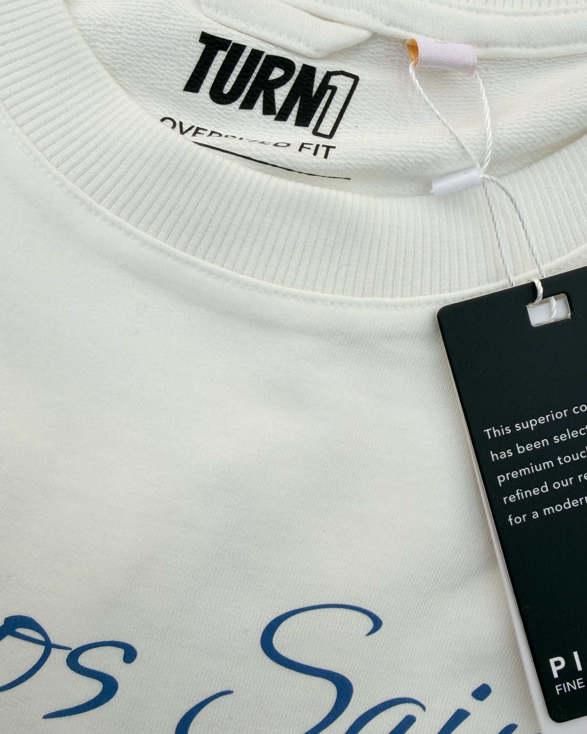 Close up of F1 Turn1 India Off White oversized unisex tshirt - fan graphic of Carlos Sainz Smooth Operator, Williams F1 racing team driver and featuring his Car Number 55.
Turn 1 label showing 100% Pima cotton seen in picture