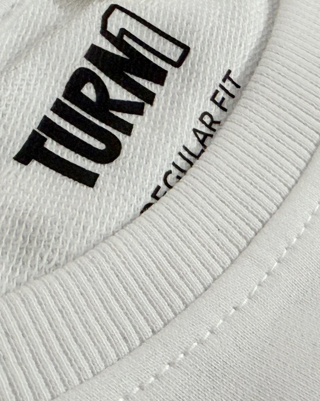 Close-up of F1 Turn1 India White crop top with “SMOOTH OPERATOR” graphic on the front based on driver Carlos Sainz Jr - driver of Williams F1 Racing team
Ribbed crew neck and “SMOOTH OPERATOR” logo detail on white crop top