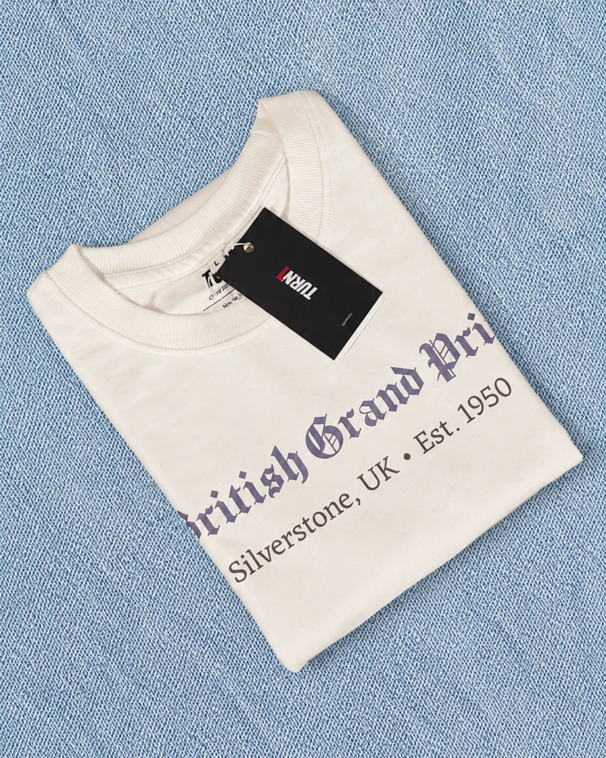 Folded Off-White British Grand Prix Graphic F1 t-shirt on light blue denim fabric background | Turn1 India