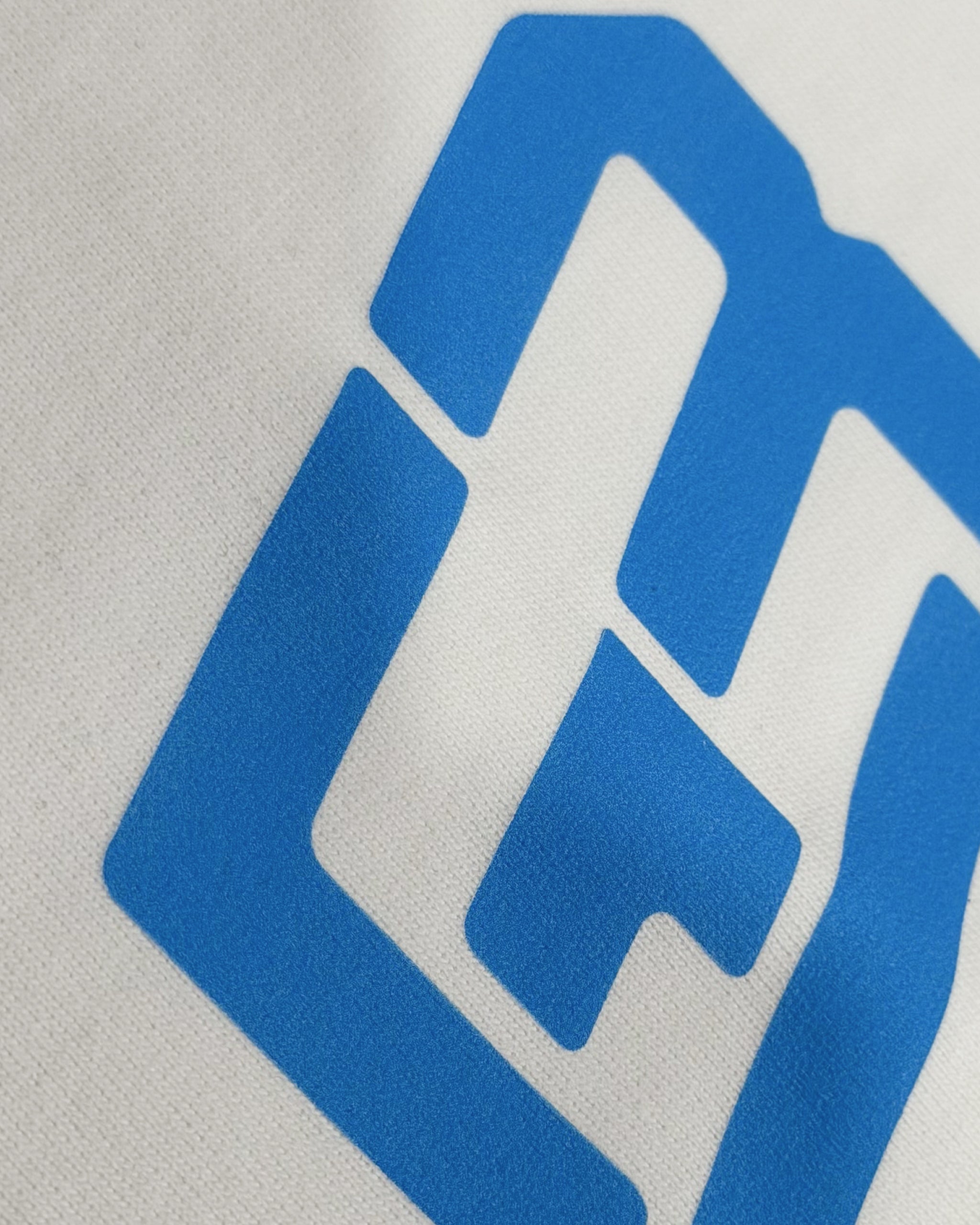 Closeup of cotton fabric and DTF print on Turn1 India F1 Tshirt Off White T-shirt: George Russell Energy front graphic with blue helmet and raised arms. Fan graphic of George Russell, driver of Mercedes AMG Petronas F1 Racing team.
Front print featuring George Russel's initials.