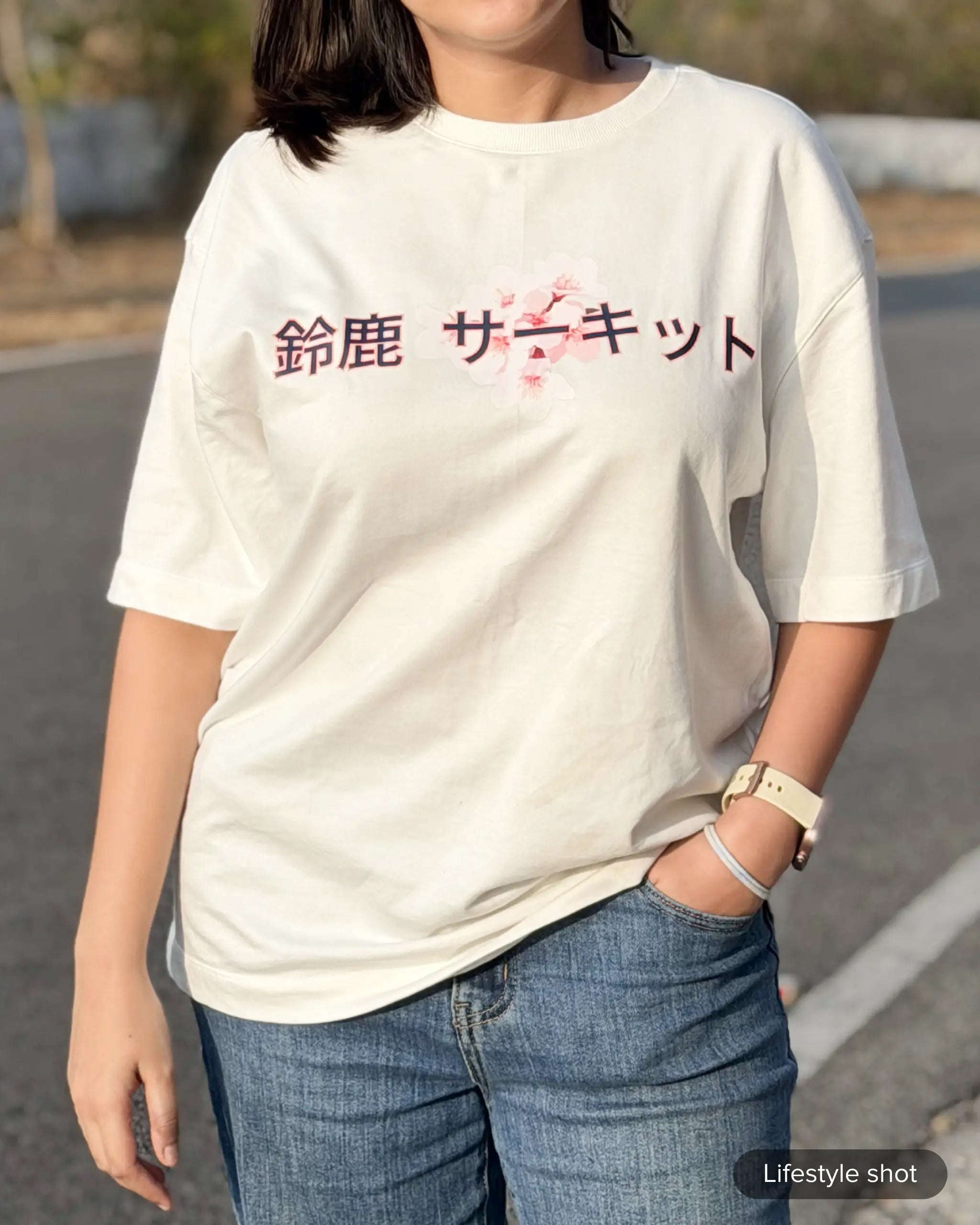 Lifestyle image of woman wearing Suzuka Circuit Japan Grand Prix F1 Unisex Oversized Graphic T-shirt Off-White Front View Natural Background | Turn1 India