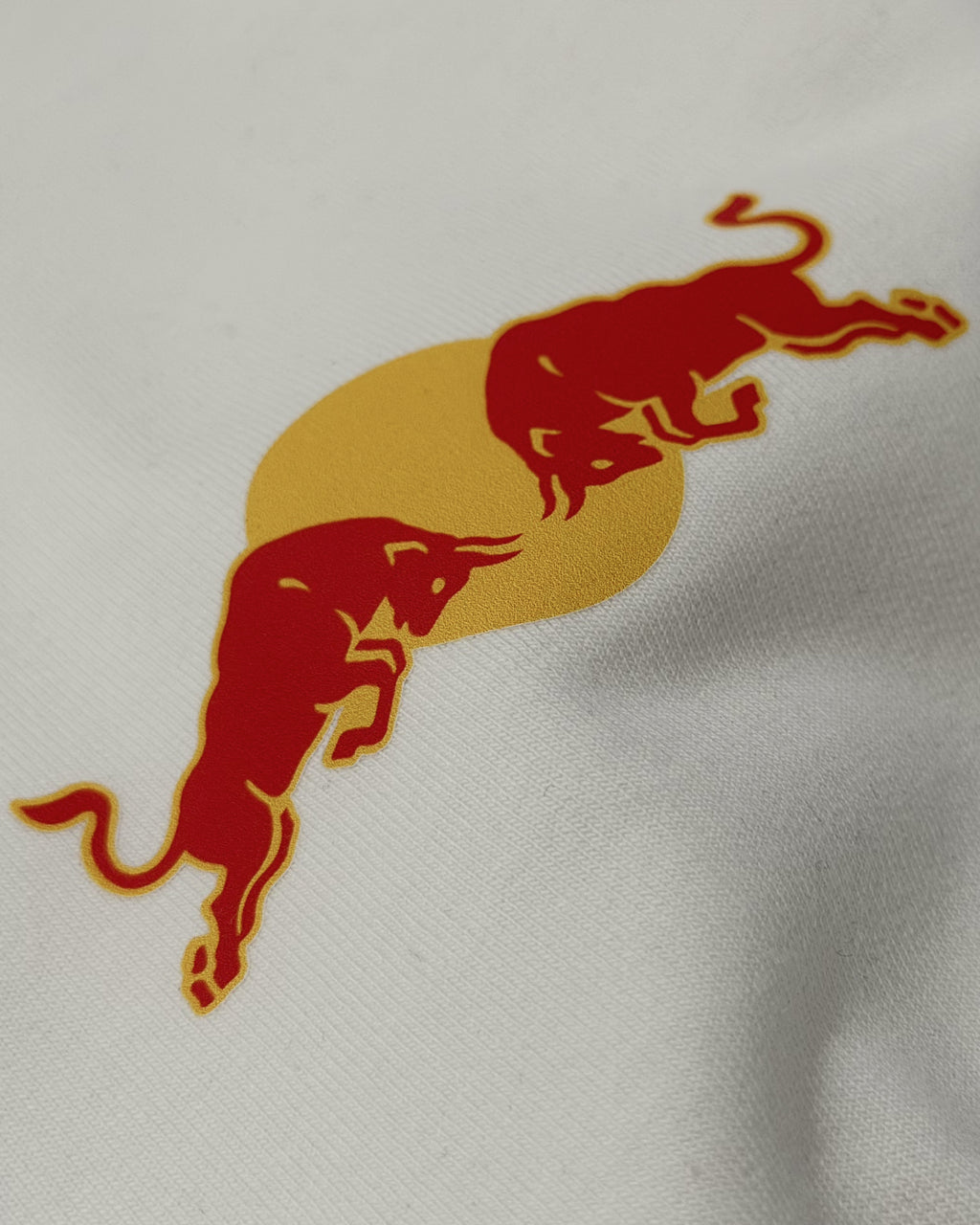 Close-up of red bull racing silhouette graphic on F1 Off White Unisex Oversized fit T-shirt by Turn 1 Brand, an F1 Apparel brand of India. Max Verrstappen fan tshirt with back print features Max Verstappen fan graphic and his name "Verstappen" in bold orange font. Frontprint features Redbull Racing F1 team logo and Max's number 3.