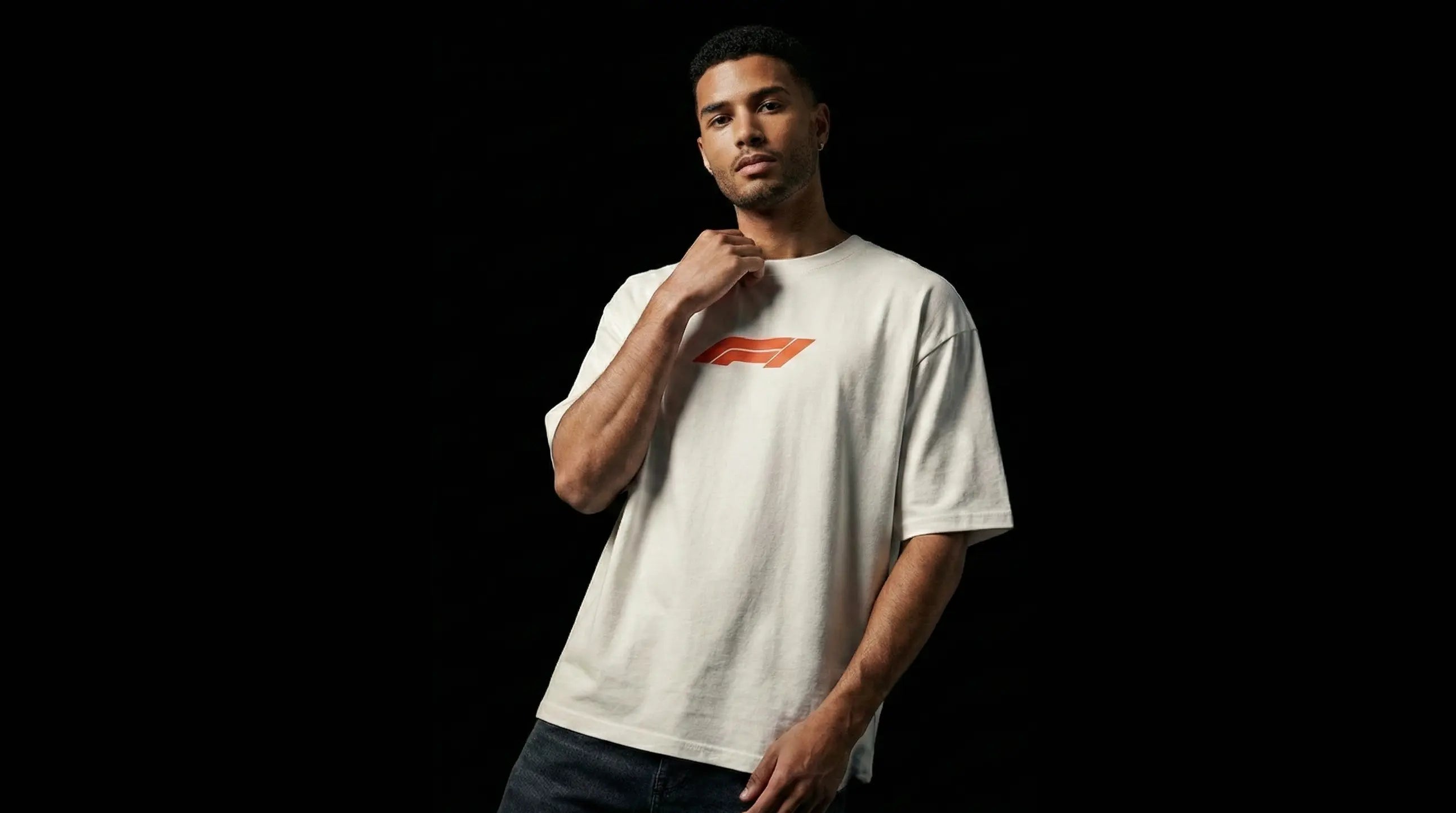 Man wearing an off-white oversized fit t-shirt with Formula 1 F1 logo against a black background