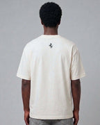 Male model wearing Vintage Ferrari F1 Turn1 India off white oversized unisex tshirt - F1 Ferrari 1954 car graphic on front along with Scuderia Ferrari Formula One Team in red