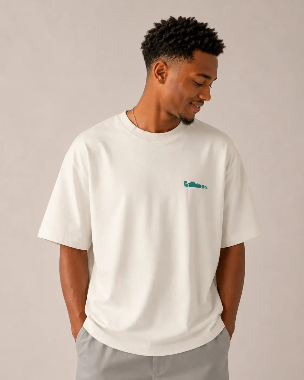 Male model wearing F1 Off-white unisex oversized T-shirt by Turn 1 Brand, an F1 Apparel brand of India. Back print features Spa Francorchamps Belgium GP F1 circuit. Front print features a miniature F1 sports car.