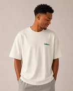 Male model wearing F1 Off-white unisex oversized T-shirt by Turn 1 Brand, an F1 Apparel brand of India. Back print features Spa Francorchamps Belgium GP F1 circuit. Front print features a miniature F1 sports car.