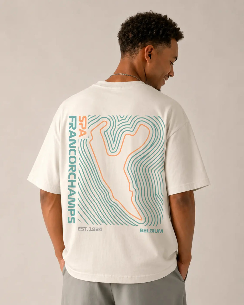 Male model wearing F1 Off-white unisex oversized T-shirt by Turn 1 Brand, an F1 Apparel brand of India. Back print features Spa Francorchamps Belgium GP F1 circuit. Front print features a miniature F1 sports car.