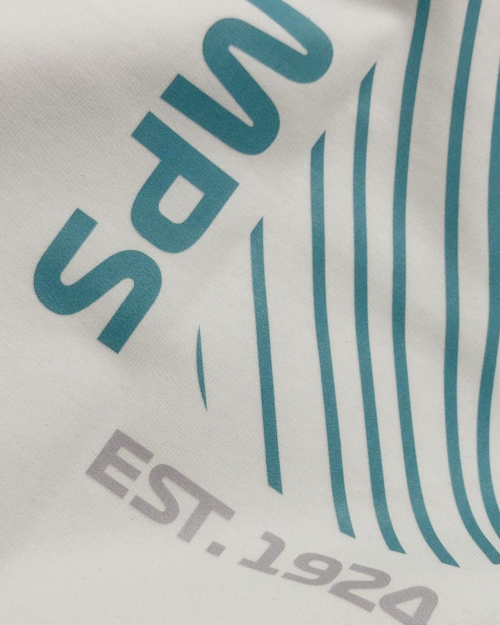 Closeup of premium cotton fabrice and print of F1 Off-white unisex oversized T-shirt by Turn 1 Brand, an F1 Apparel brand of India. Back print features Spa Francorchamps Belgium GP F1 circuit. Front print features a miniature F1 sports car.