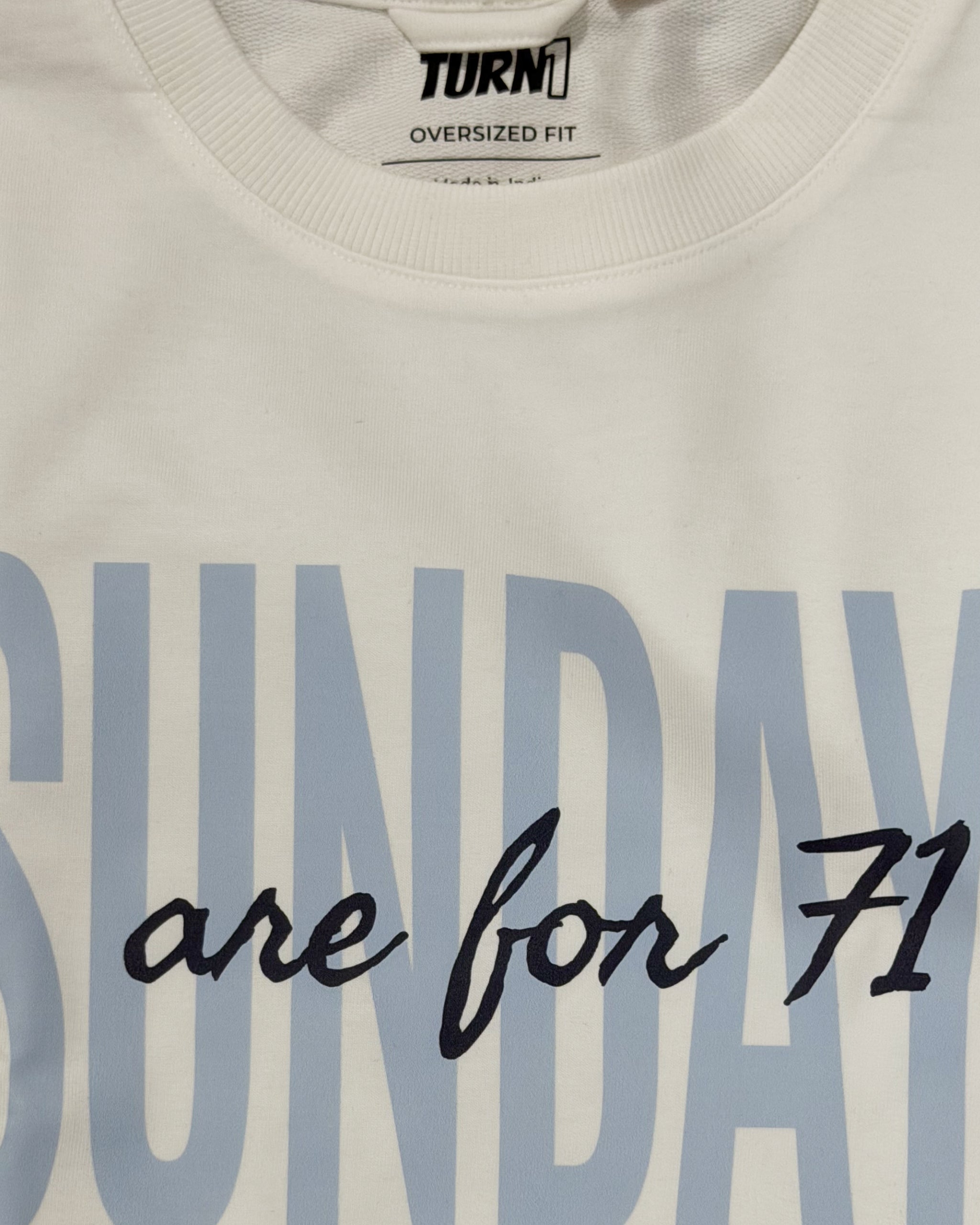 Cuello redondo y etiqueta “Turn1 Oversized Fit” en camiseta off-white con “Share for 71”